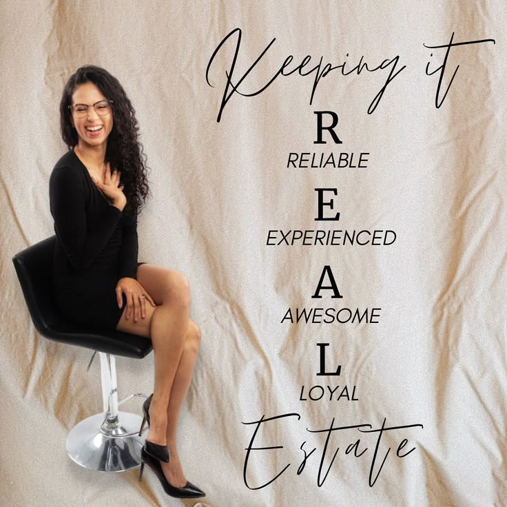 a woman sitting on top of a black chair next to a white backdrop with words