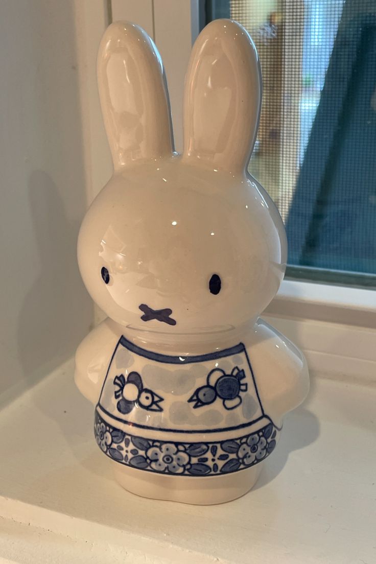 a white ceramic rabbit figurine sitting on top of a counter next to a window