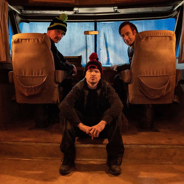 three men sitting in the back of a bus with their hands on their hipss