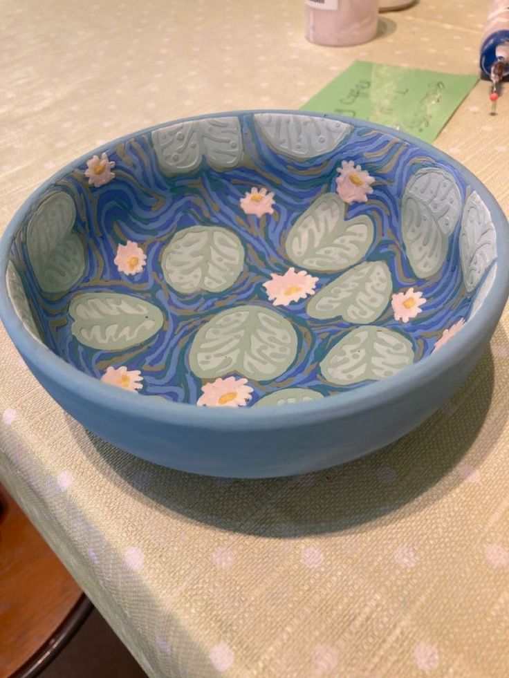 a blue bowl sitting on top of a table next to a white and green cloth