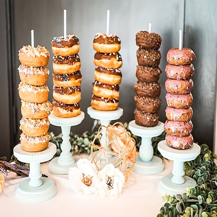 there are many donuts on the table and one is stacked high with candles in it