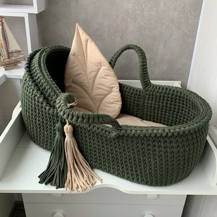 a large green basket with a tassel hanging from it's side on top of a white dresser