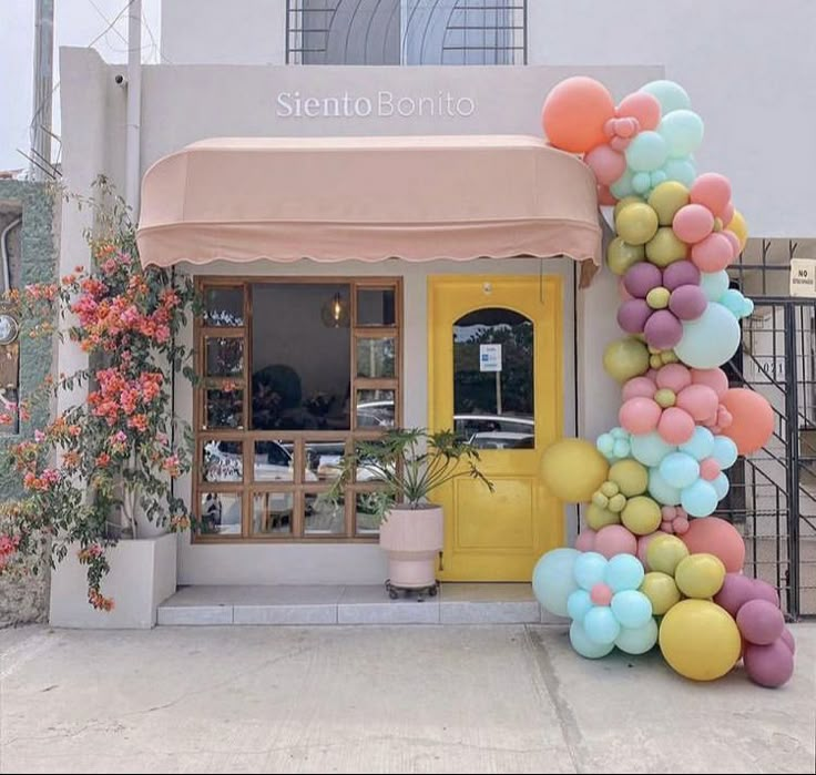 there is a large number made out of balloons in front of a building with pink and yellow flowers