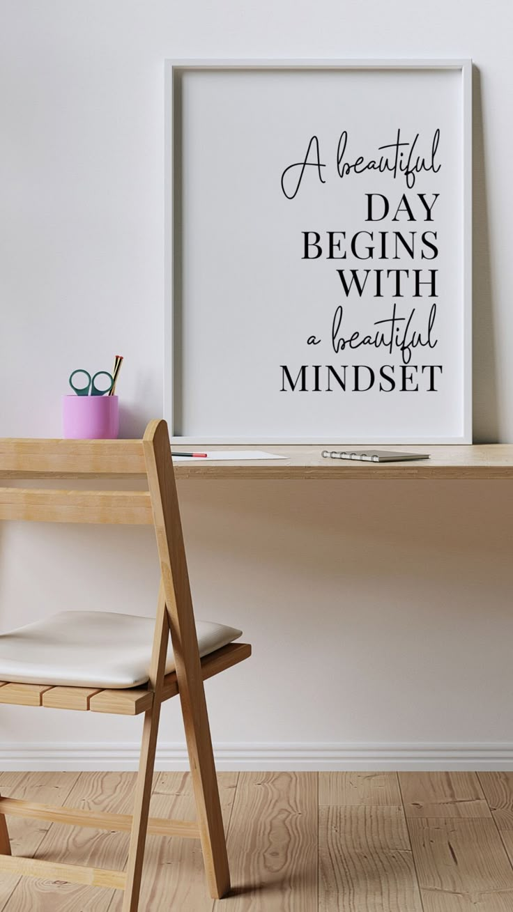 a chair sitting in front of a desk with a poster above it that says, a beautiful day begins with a beautiful mindset