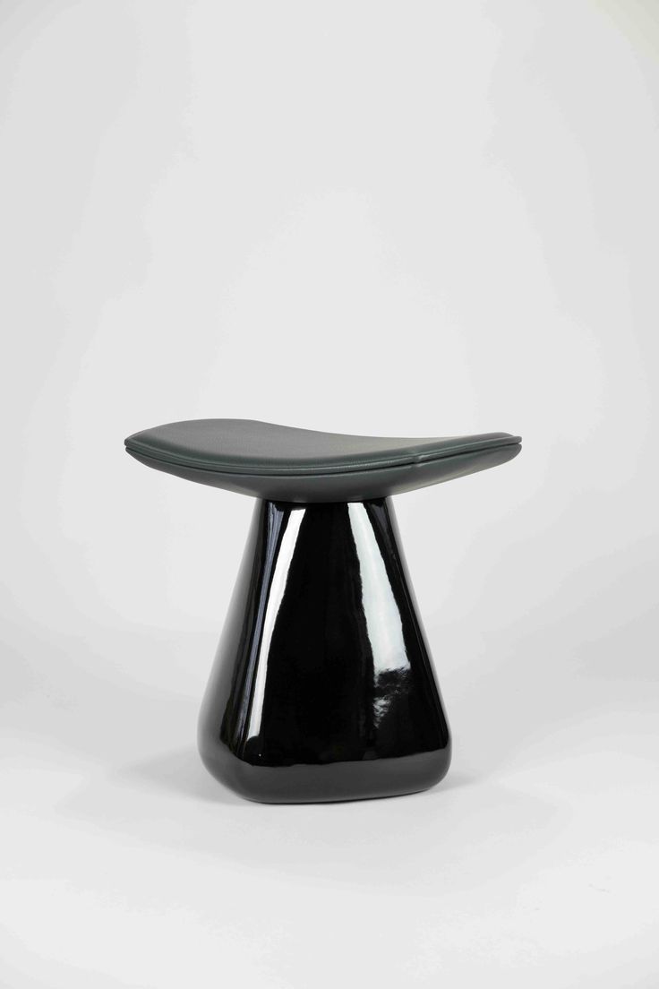 a black table with a curved top on a white surface in front of a plain background