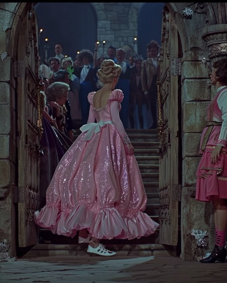 two women in pink dresses standing at the entrance to a castle with lots of people