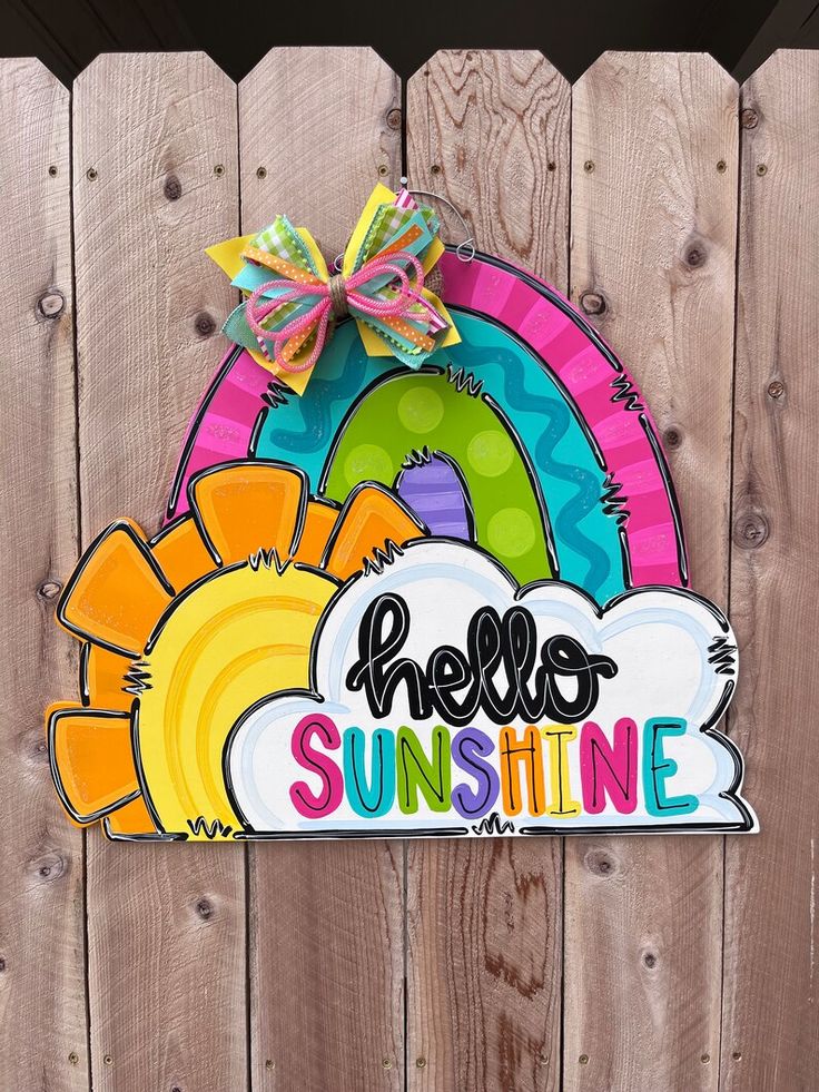 a sign that says hello sunshine on the side of a wooden fence with a rainbow