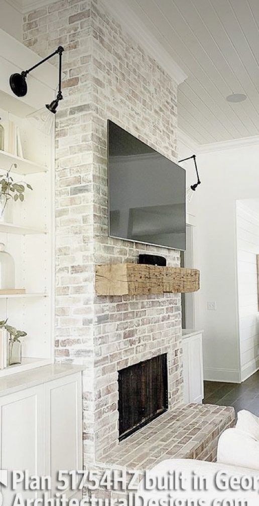 a living room with a large flat screen tv mounted to the side of a brick fireplace