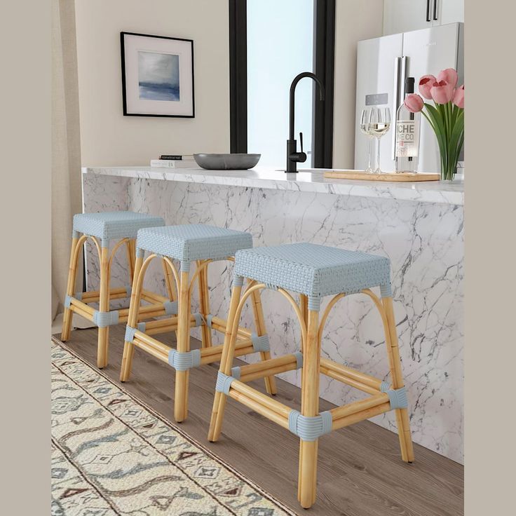 three stools in front of a counter with flowers on it and an area rug