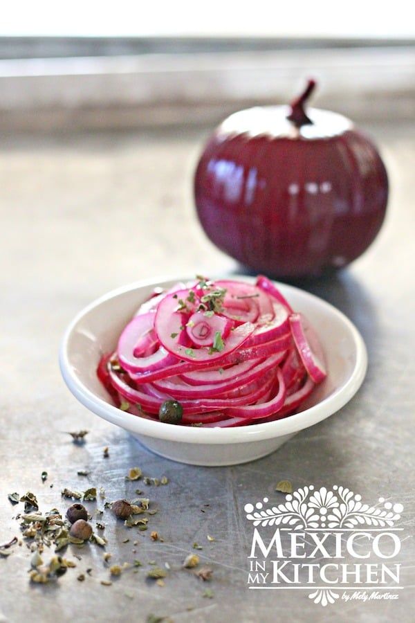 a bowl filled with sliced red onions next to an onion on top of a table