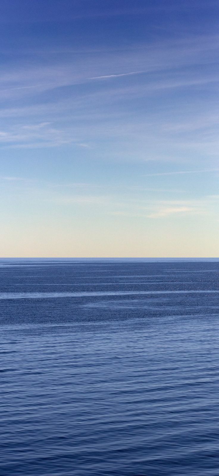 a lone boat floating on the ocean under a blue sky