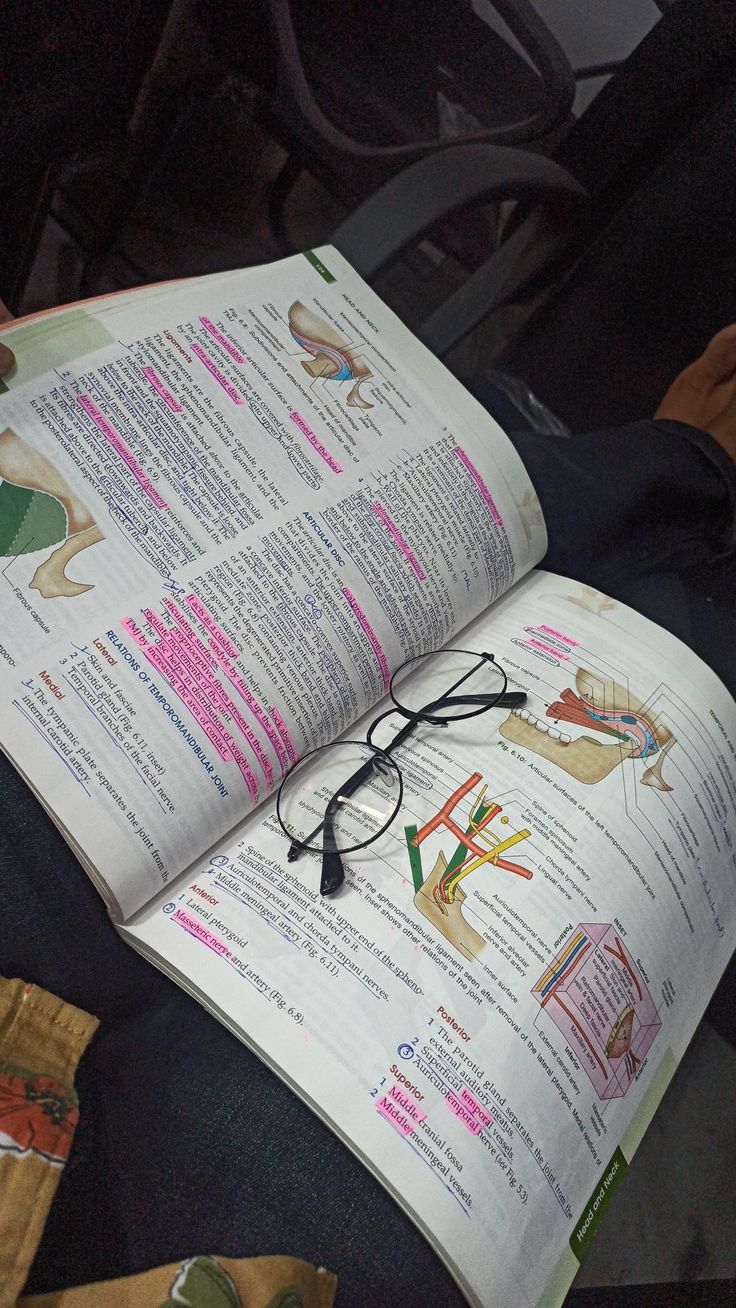 an open book sitting on top of a chair next to a pair of eyeglasses