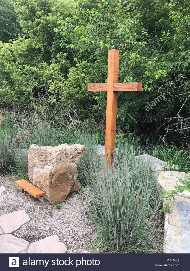 a wooden cross in the middle of a garden