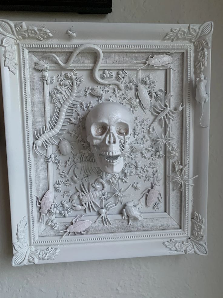 an intricately carved white frame with a skull in the center