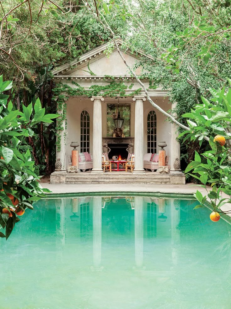 an image of a house with a pool in the foreground and trees surrounding it