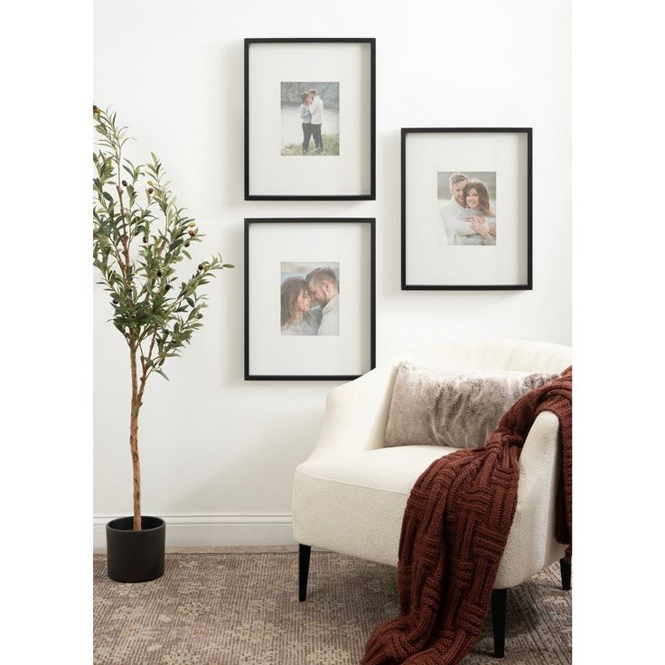 three framed pictures hang on the wall next to a white chair with a red blanket