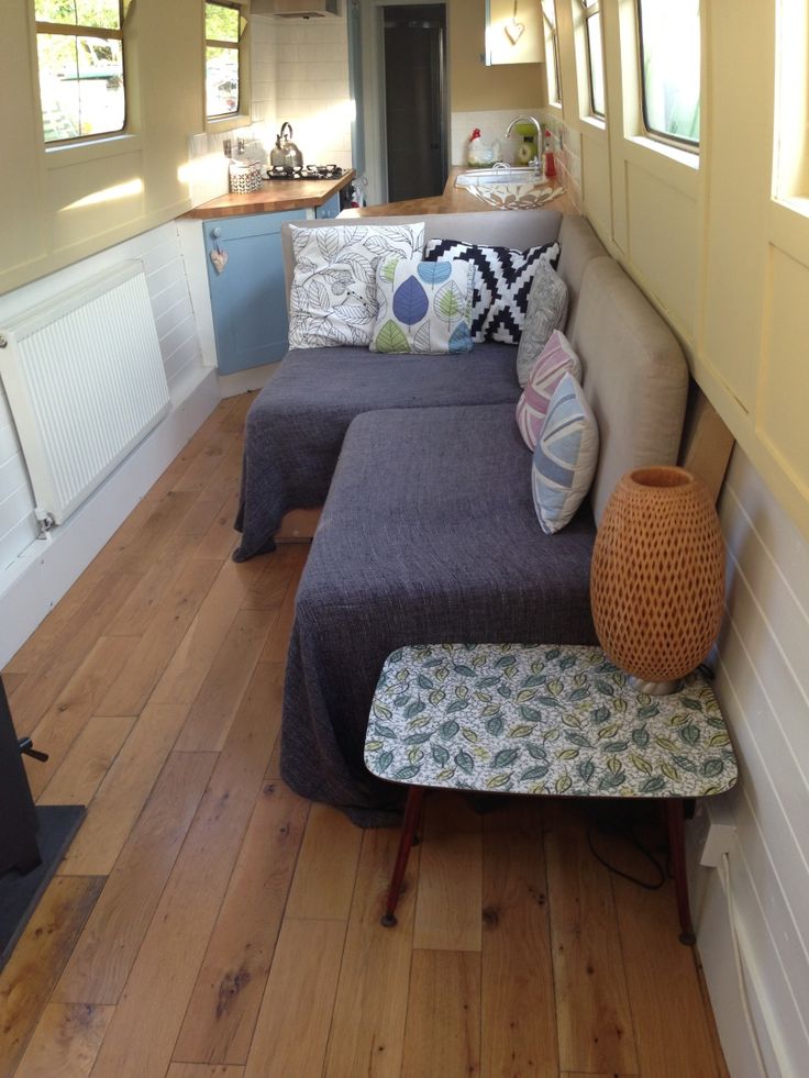 a living room with couches and pillows on the wooden floor in front of an open kitchen