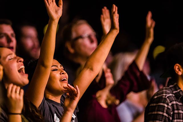 a group of people clapping and standing in front of each other with their hands up