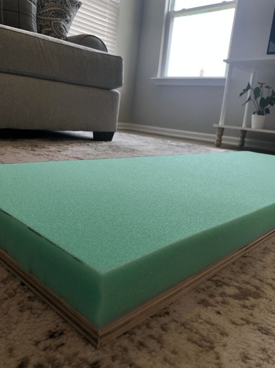 a green mattress on the floor in front of a couch