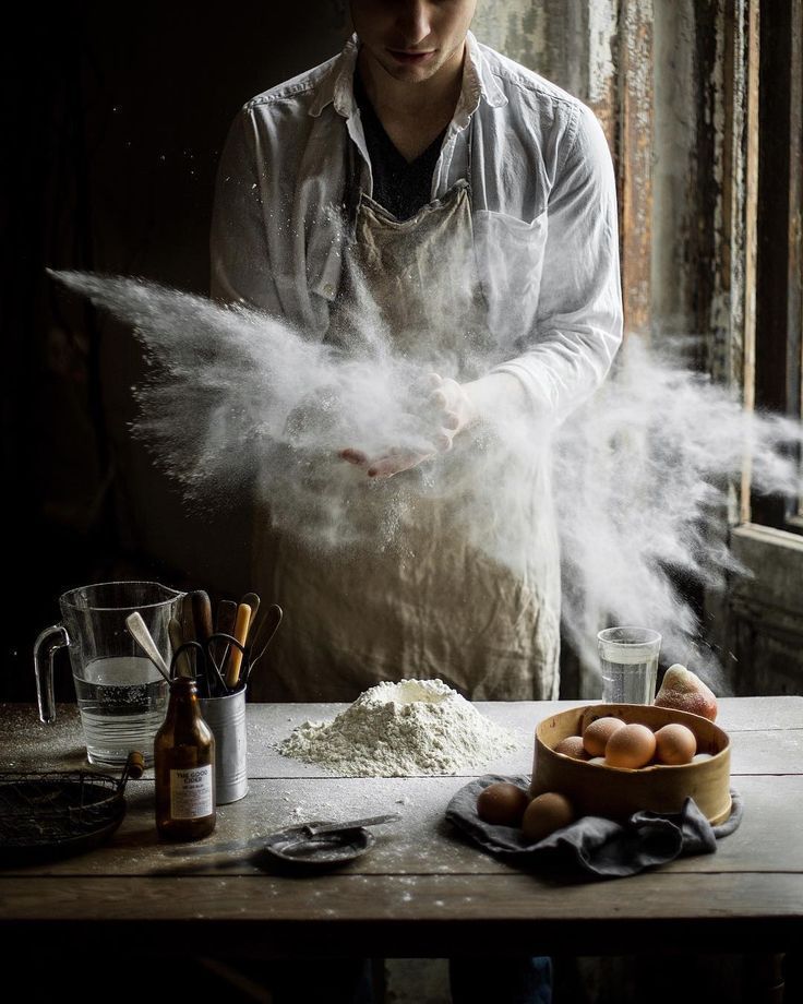 a man standing in front of a table covered in flour and other items, with the words black pizza written on it