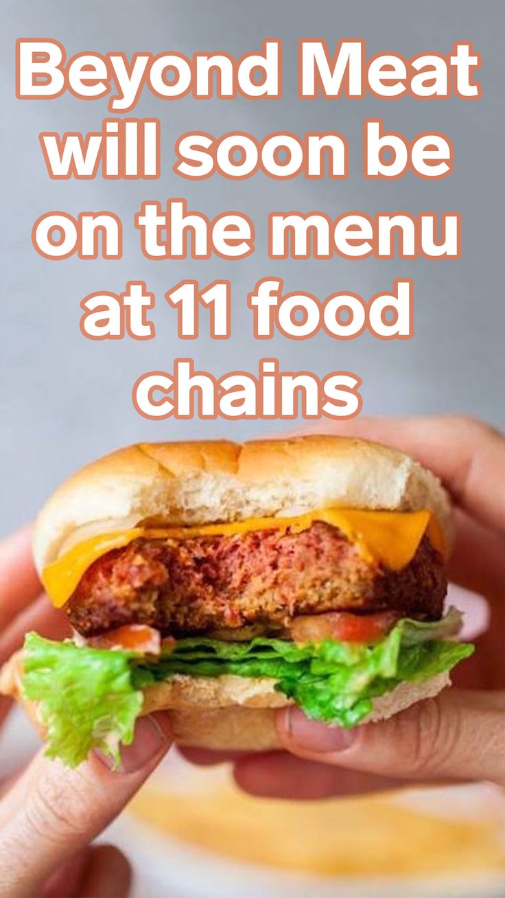 a hand holding a hamburger with lettuce and tomato on it, in front of a plate that says beyond meat will soon be on the menu at 11 food chains