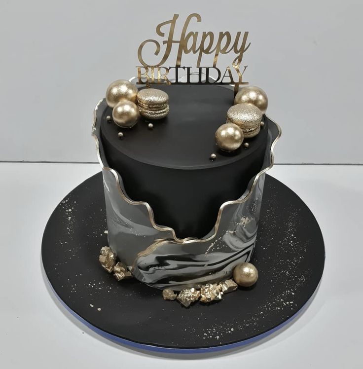 a black and silver birthday cake with gold decorations