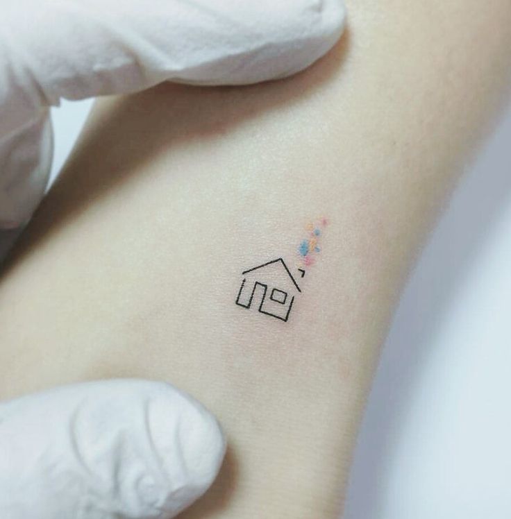 a small house tattoo on the back of a woman's left arm