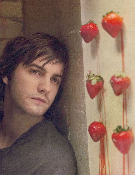 a man leaning against a wall with strawberries on it