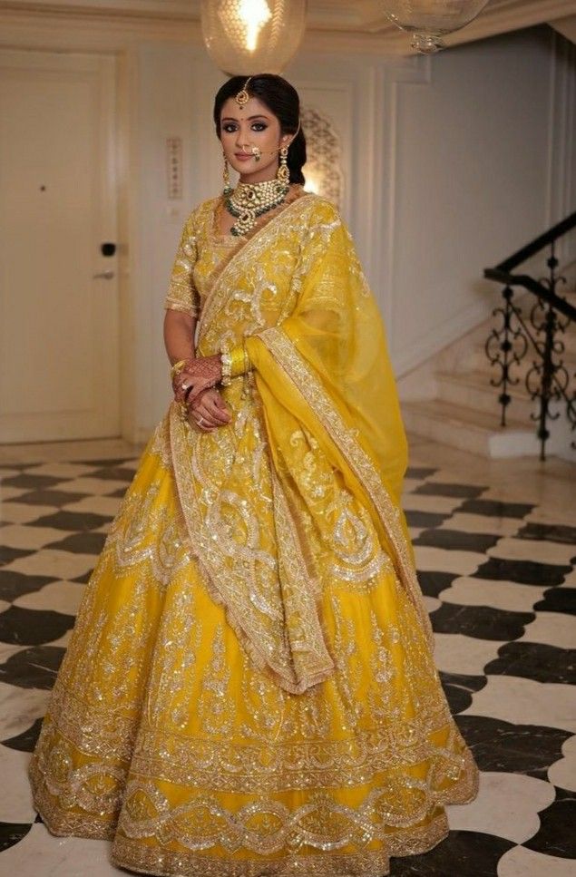 a woman in a yellow and gold bridal gown standing on a checkered floor