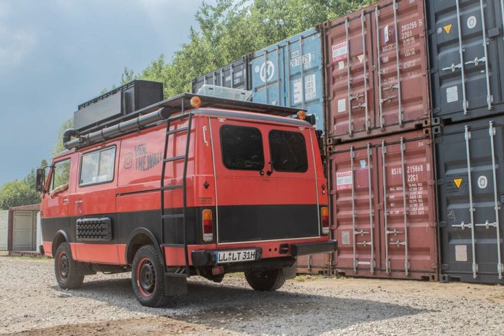 a red and black truck parked next to some cargo containers