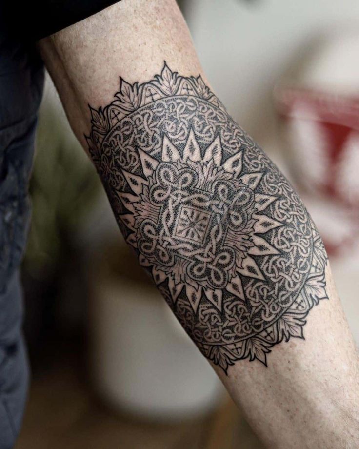 a man's arm with a tattoo on it that has an intricate design in the middle