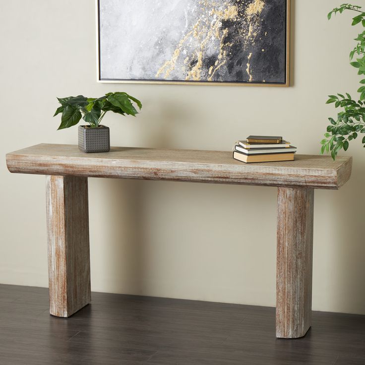 a wooden table with two books and a potted plant on it in front of a painting