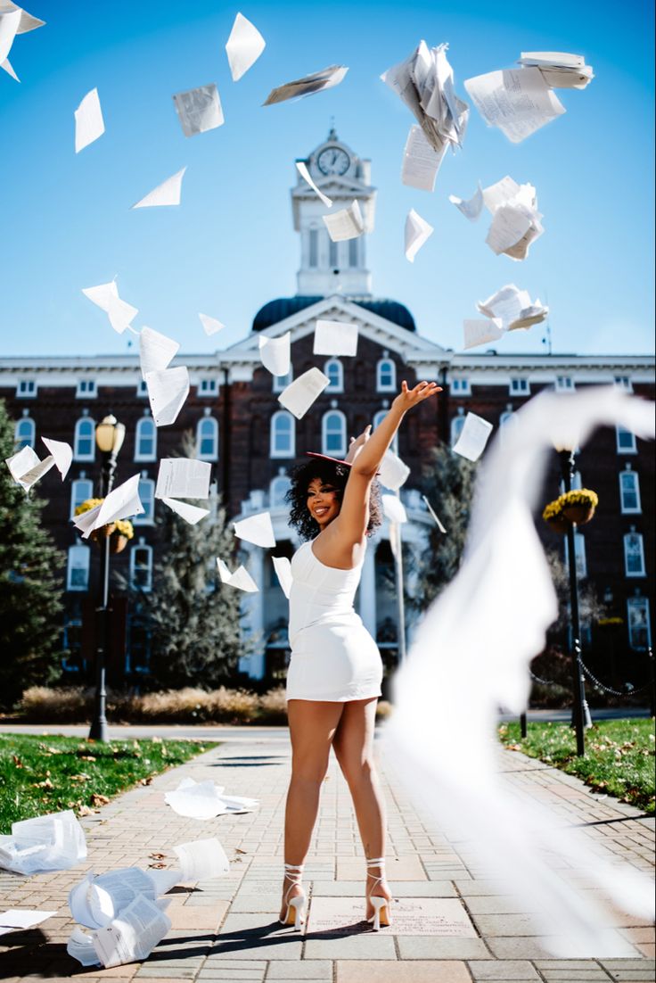 a woman in white dress throwing papers into the air with her arms outstretched and legs spread out