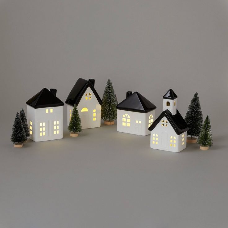 a group of small white houses with lights on them and trees in the foreground