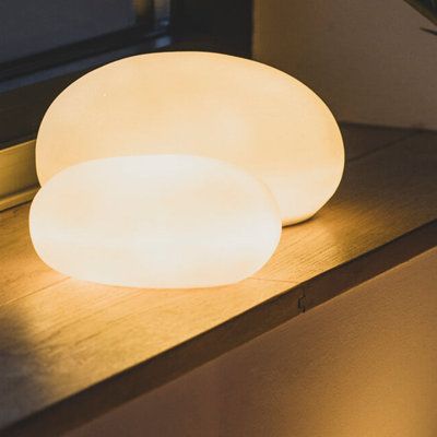 an illuminated lamp sitting on top of a wooden table next to a window sill