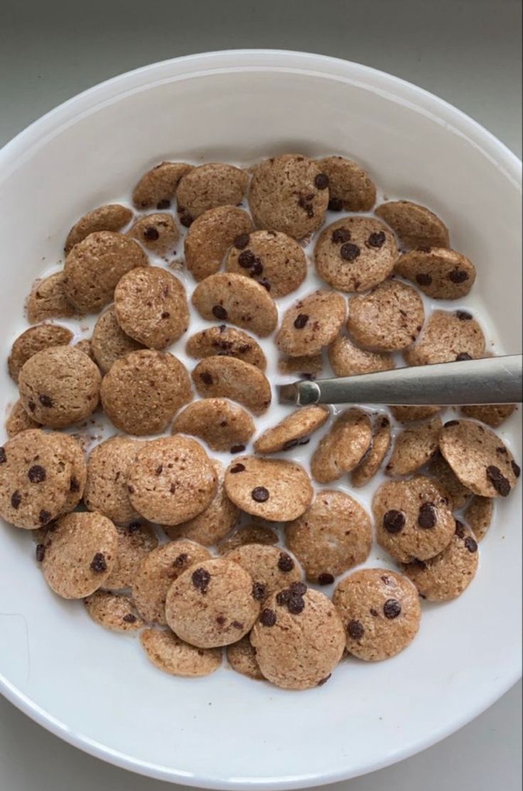 a white bowl filled with cereal and chocolate chip cookie cookies on top of a table