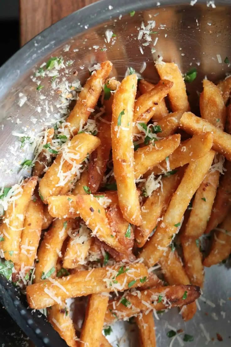 french fries with parmesan cheese and herbs in a metal bowl on a wooden table