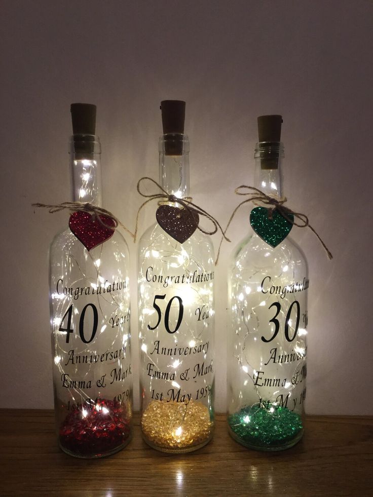 three bottles with lights in them on a table