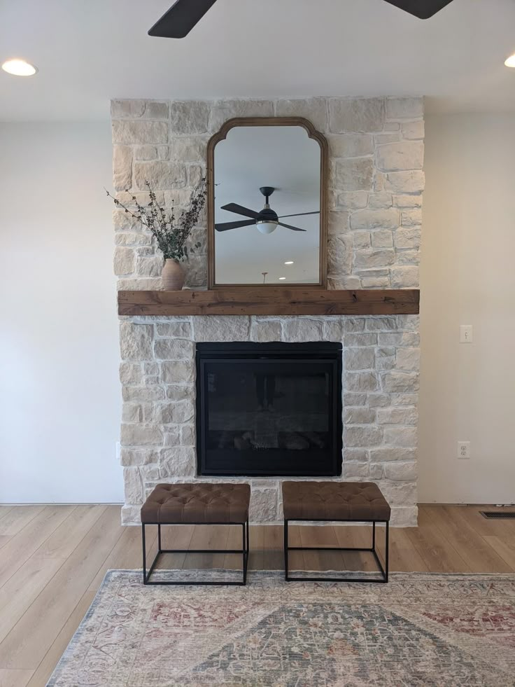 a living room with a fireplace, mirror and ottoman