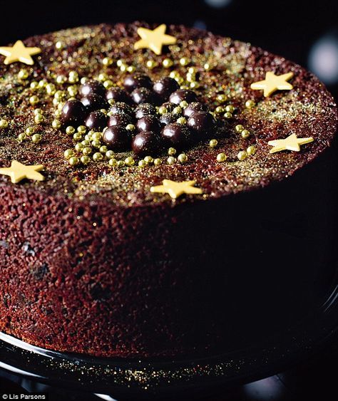 a chocolate cake with gold stars on top is sitting on a black plate and looks like it has been baked