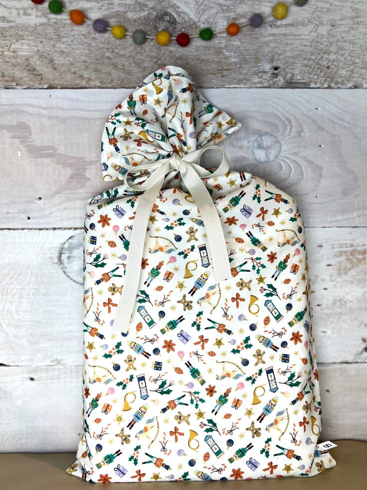 a drawsack bag with an assortment of sewing related items on it, tied to a wooden background