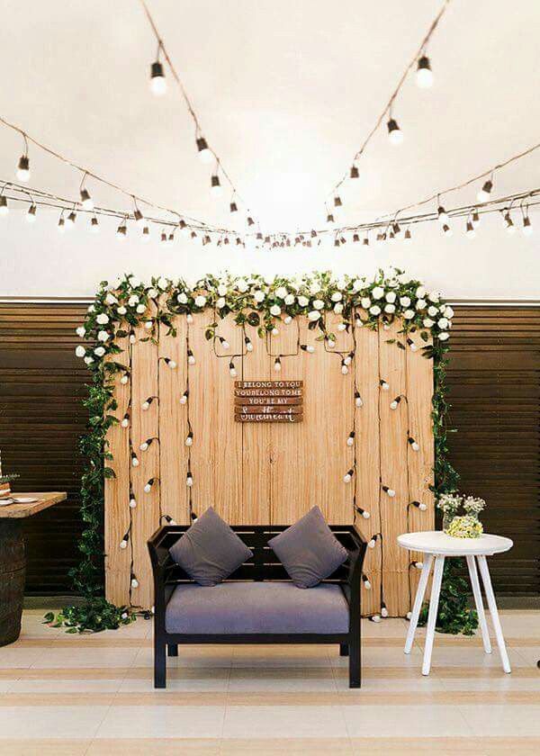 a room decorated with lights and flowers on the wall, two couches in front of a wooden screen