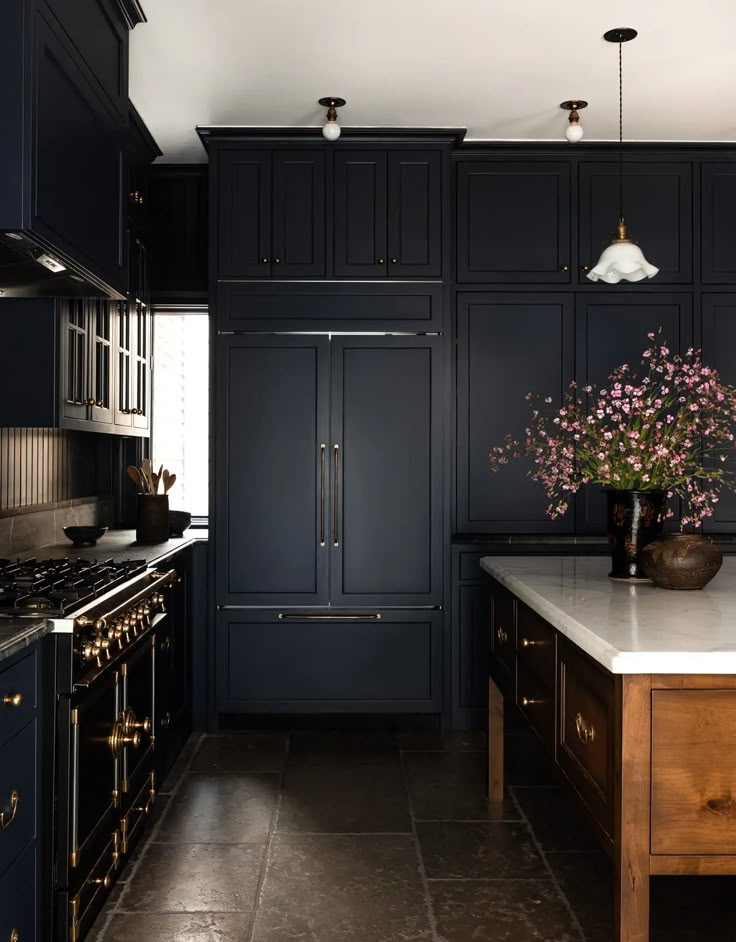 a kitchen with dark blue cabinets and marble counter tops