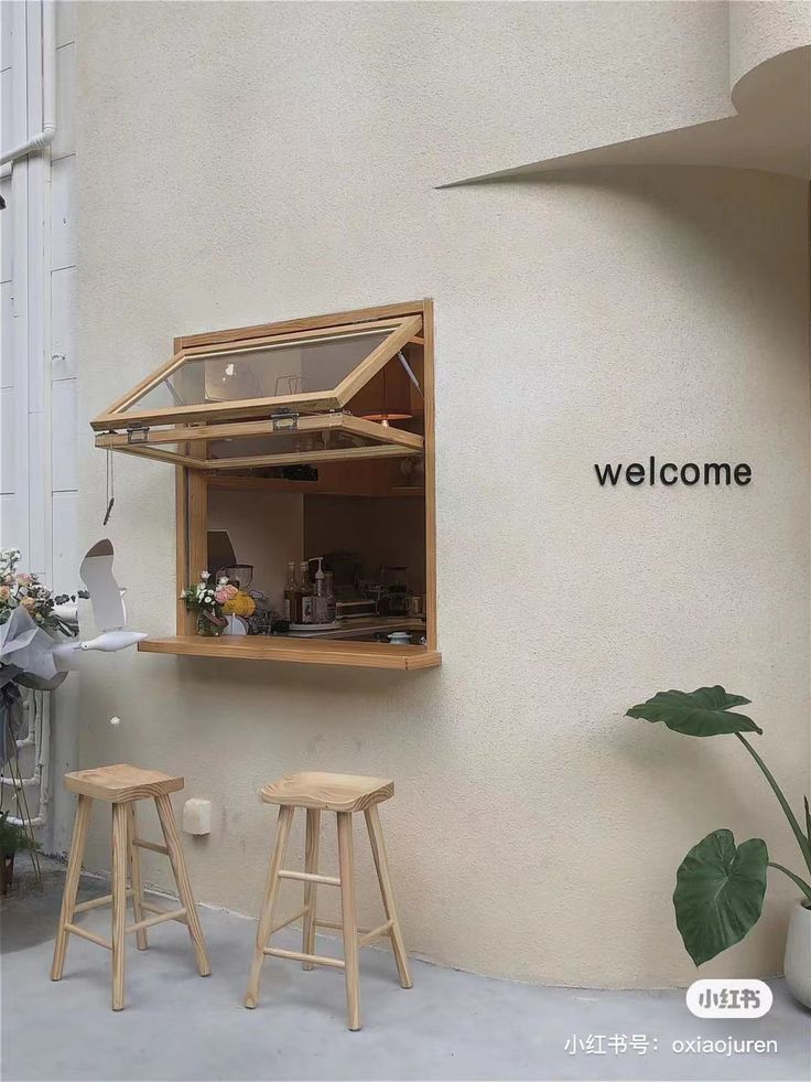 an open window on the side of a building with two stools in front of it