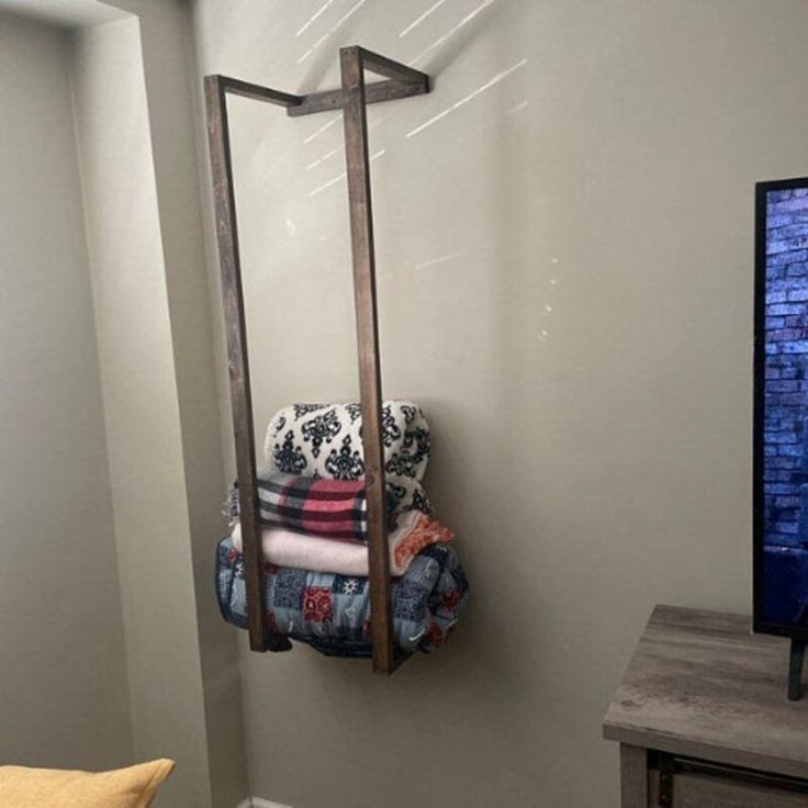 a towel rack in the corner of a room next to a bed and television set