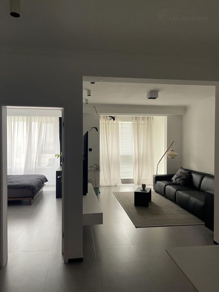 an empty living room with white walls and flooring is seen through the open doorway