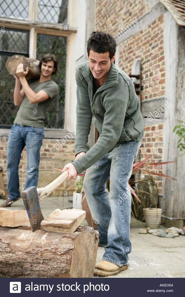 two men in the process of chopping wood with an ax