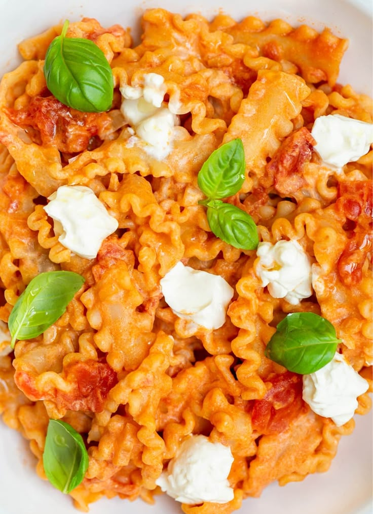 a white plate topped with pasta covered in tomato sauce and fettuccine cheese