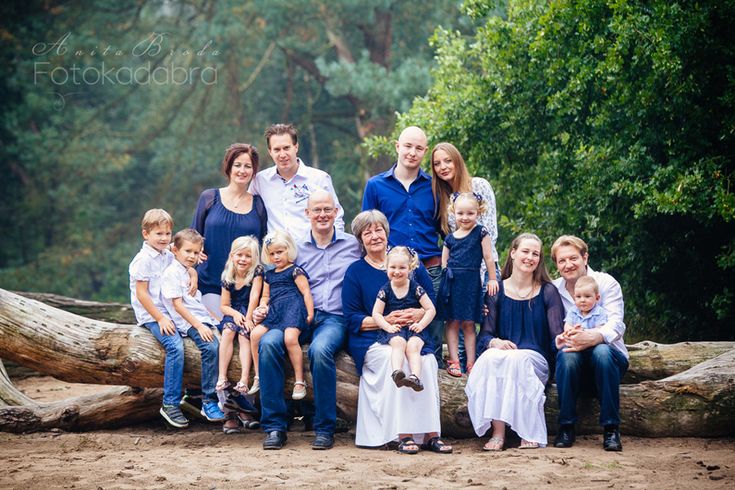 a large family poses for a photo in front of some fallen trees and green foliage