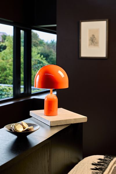 an orange lamp sitting on top of a table next to a window